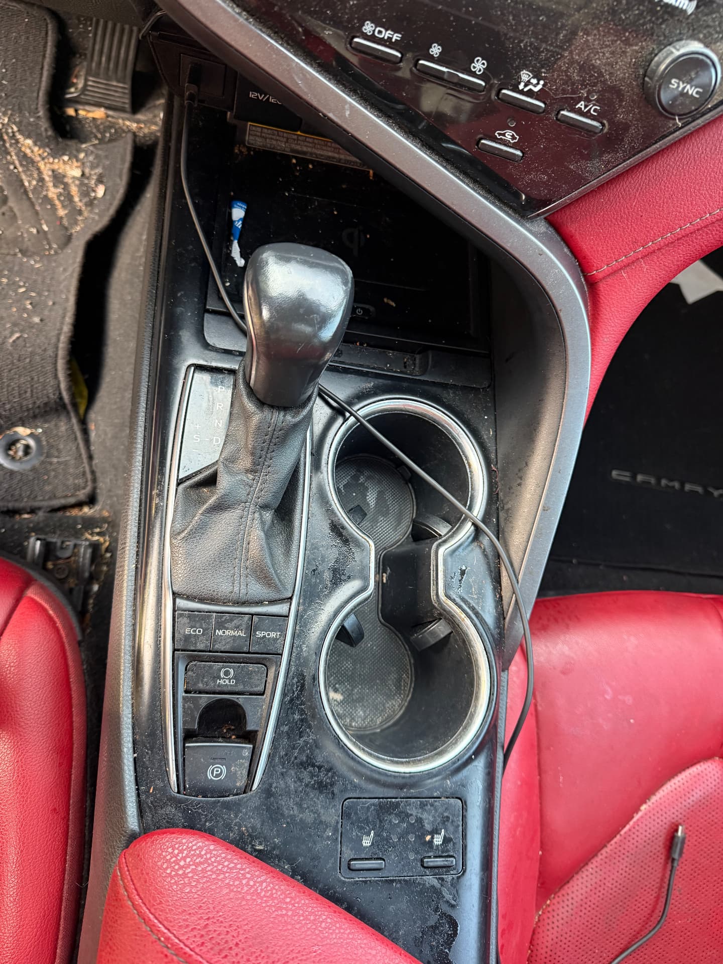Dirty Toyota Camry center console, shifter and cup holders covered in dust and grime before detailing